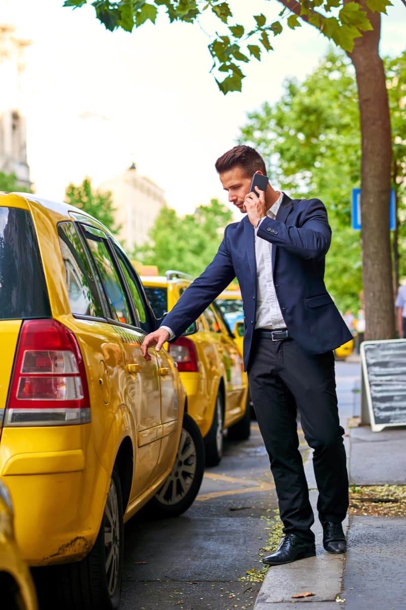 Business traveller arranging transport beside a taxi