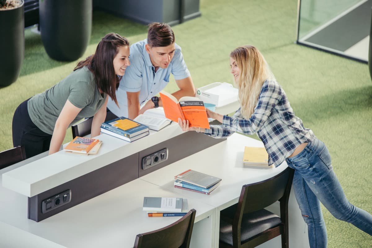 Students collaborating at a shared table in a modern common area