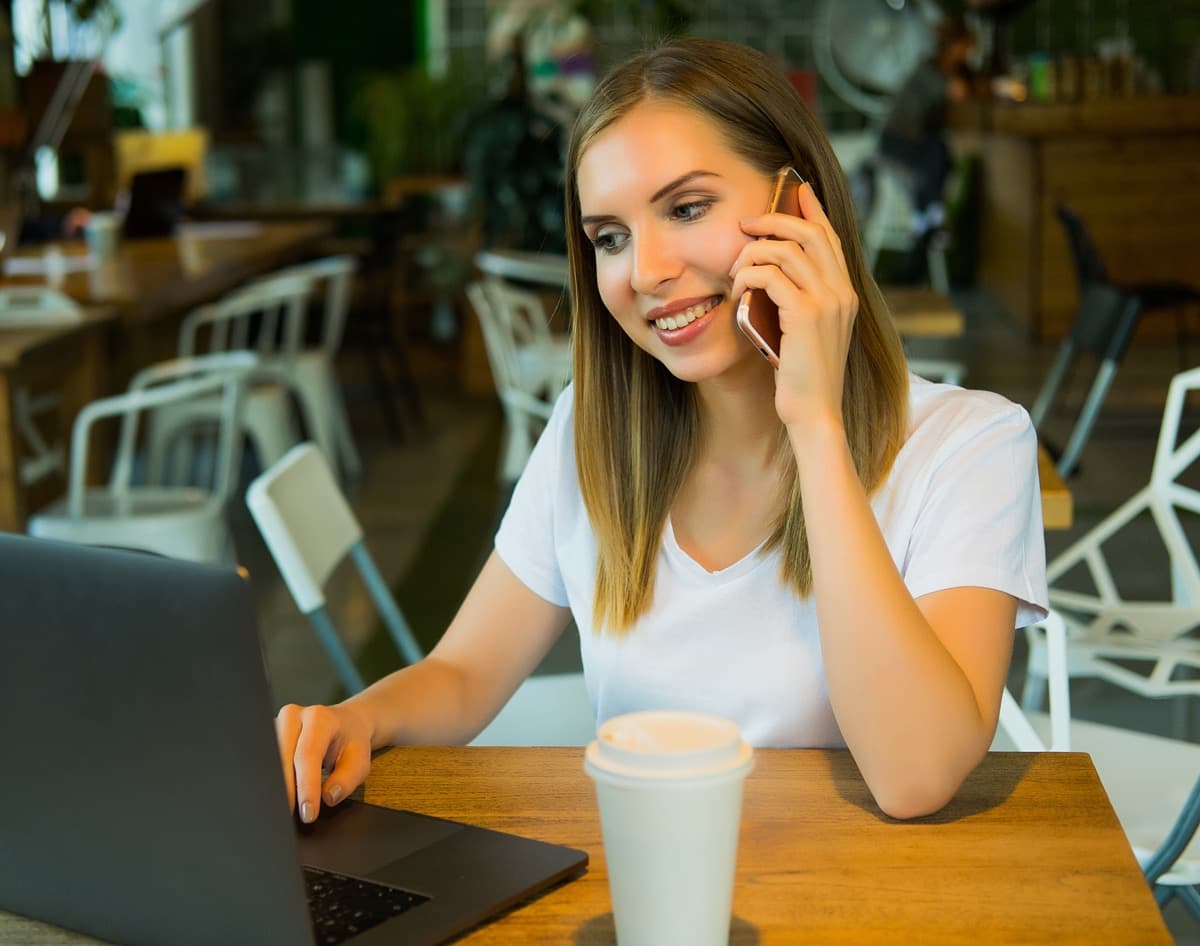 Holiday guest coordinating travel plans on phone and laptop with support