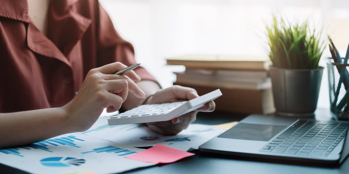 Finance administrator reconciling relocation invoices with a calculator