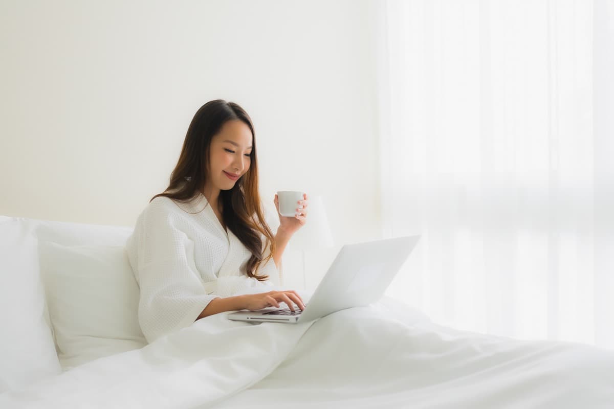 Patient resting in bed while using a laptop to review accommodation options